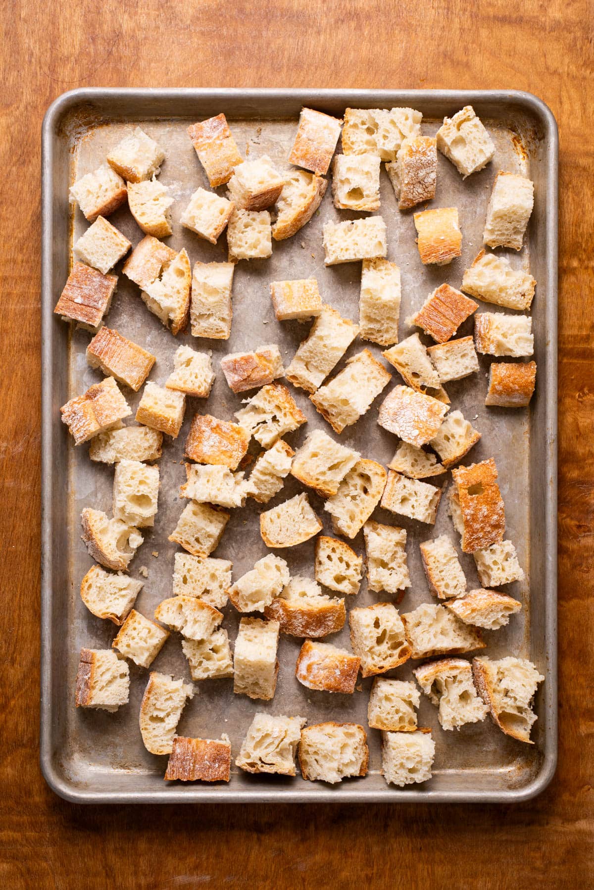 Ciabatta bread cubes on a baking sheet.