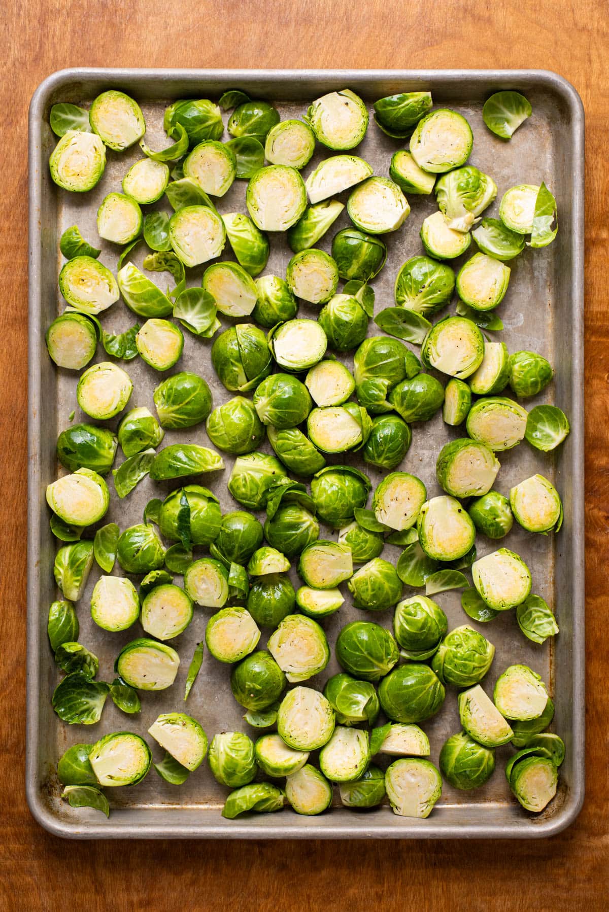 Raw halved Brussels sprouts on a baking sheet.