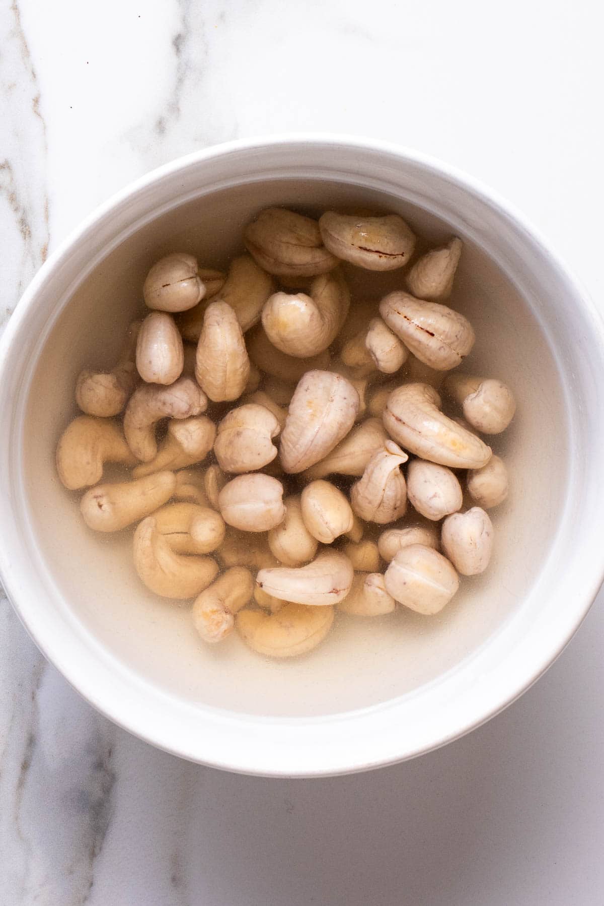 Raw cashews soaking in a bowl of water.