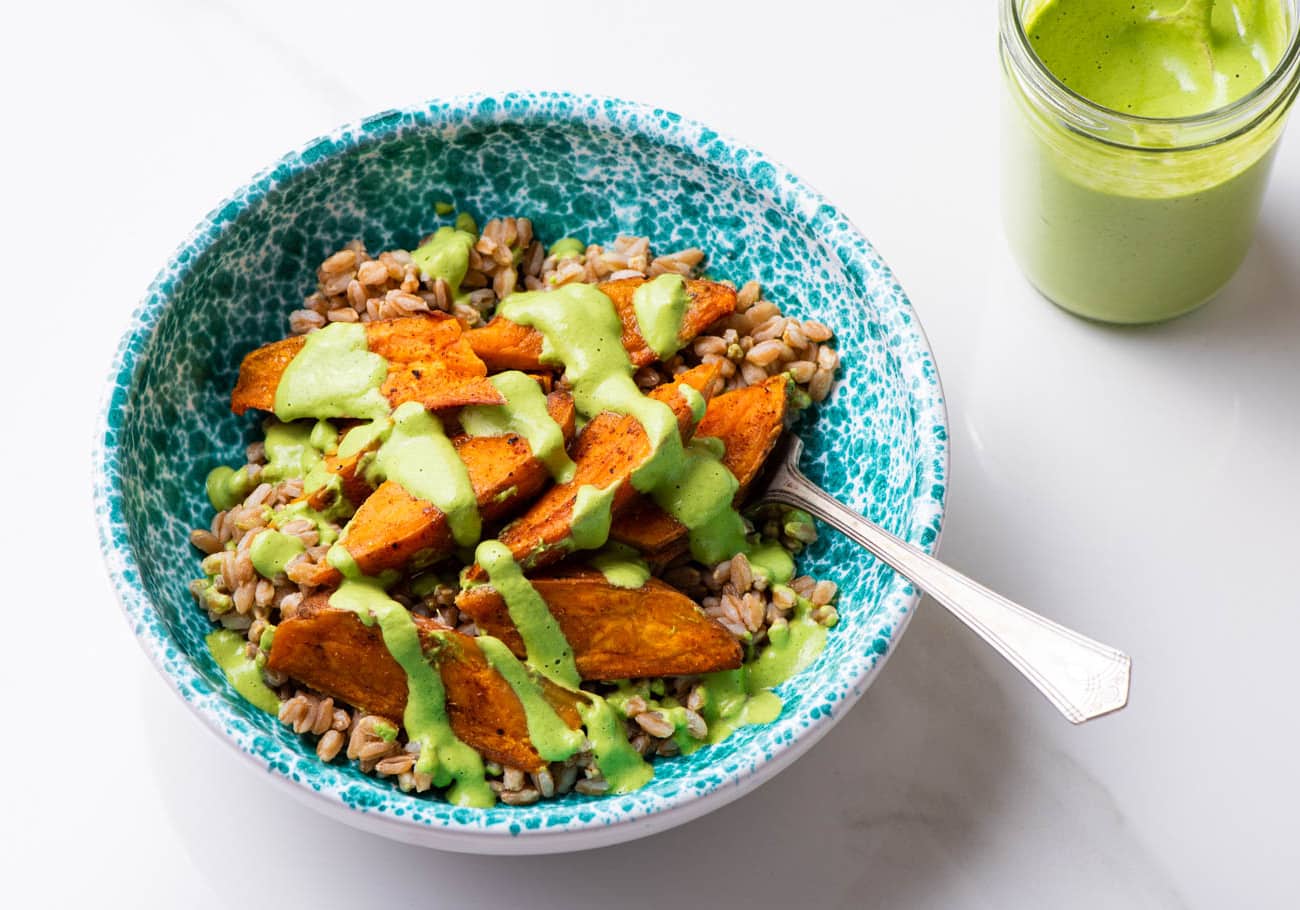 Creamy cilantro sauce drizzled on a bowl of farro and sweet potatoes.