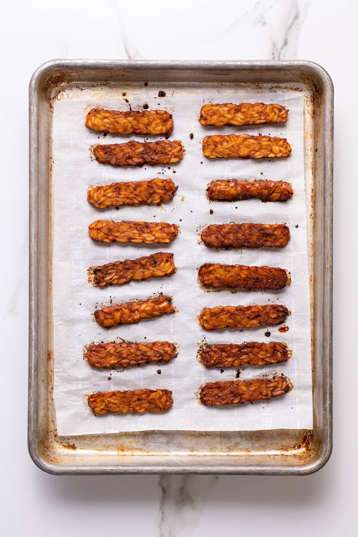 Baked tempeh strips on a baking sheet.