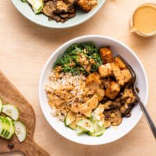 Tofu rice bowls with kale, mushrooms, cucumbers, and peanut sauce.