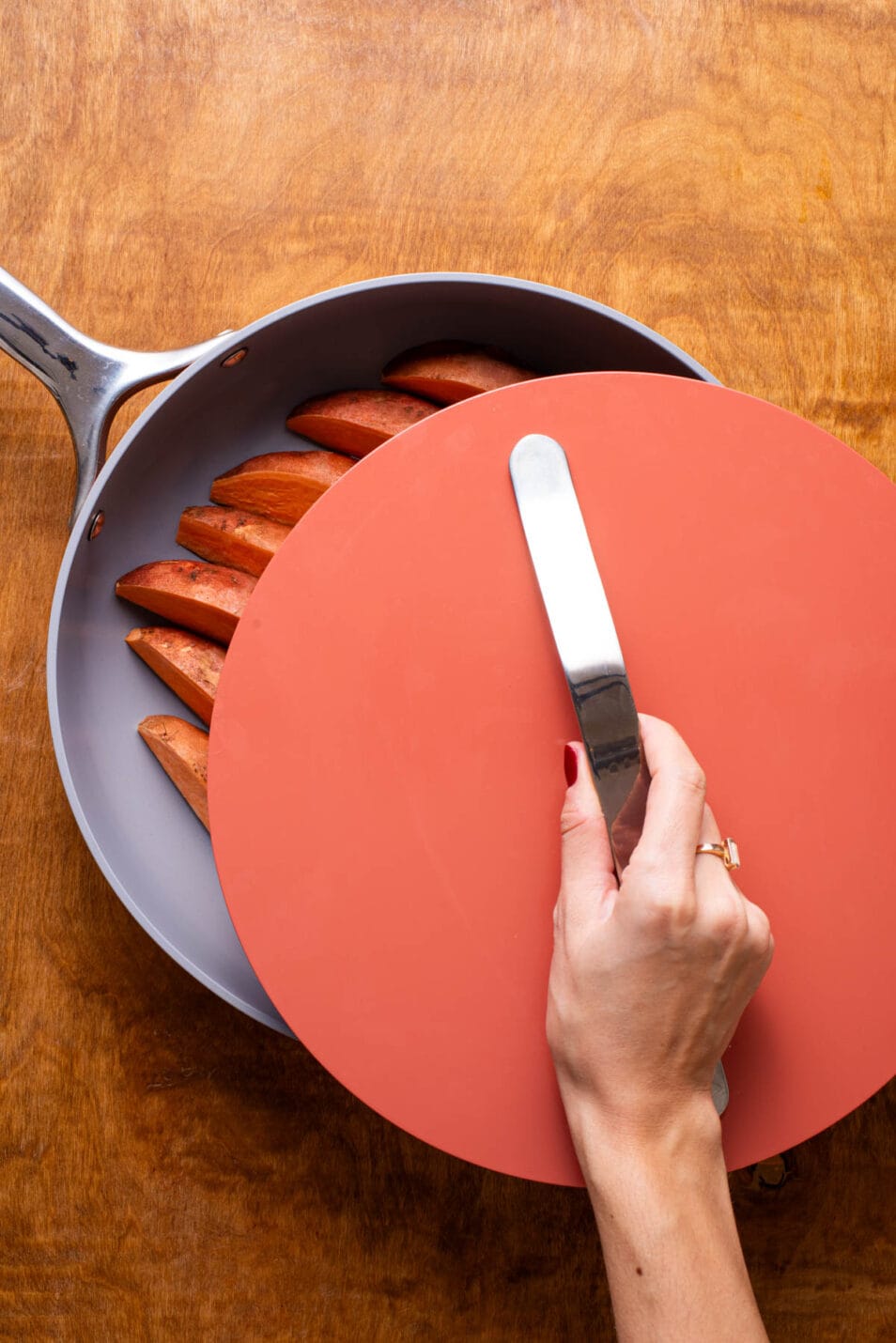 Woman's hand covering skillet with lid.