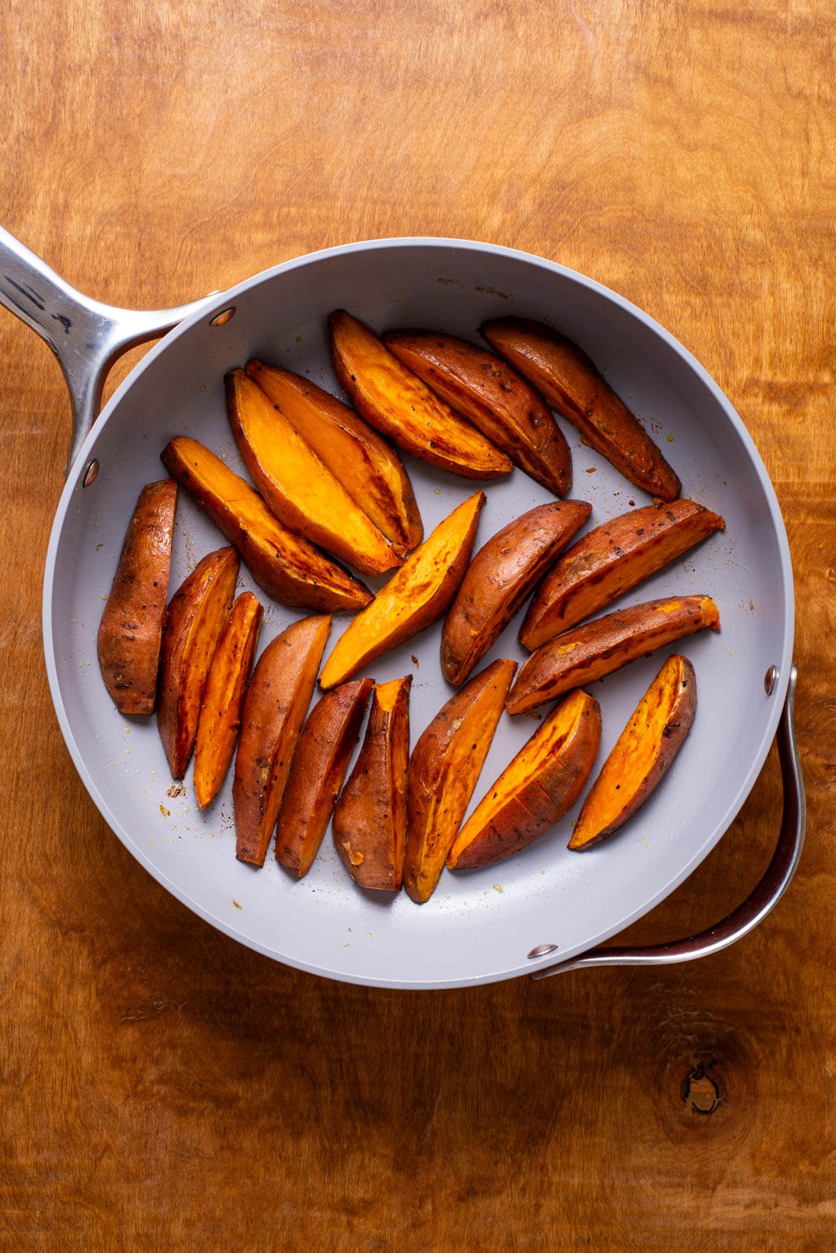 Cooked sweet potato wedges in a skillet.