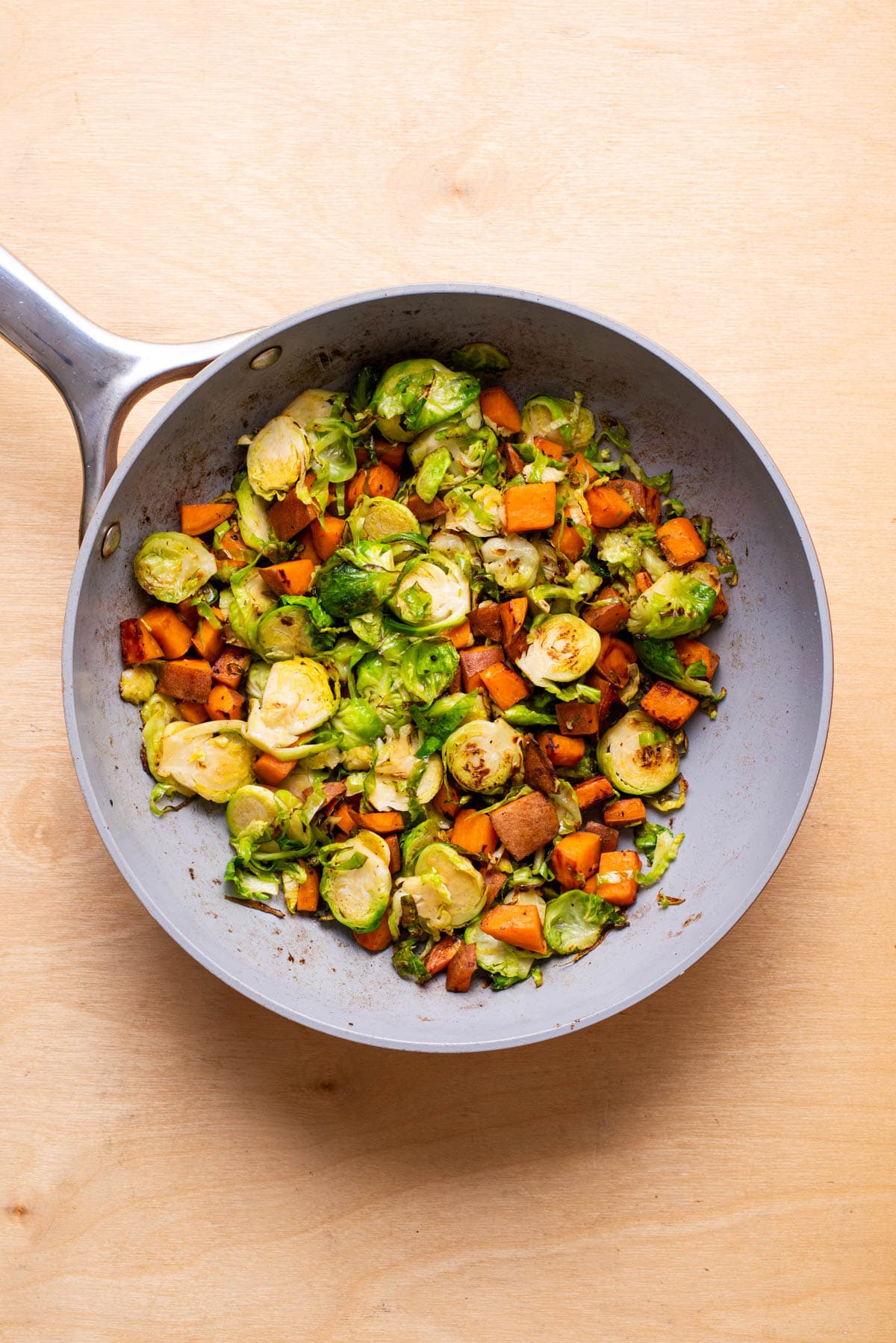 Diced sweet potatoes and shredded brussels sprouts in a skillet.