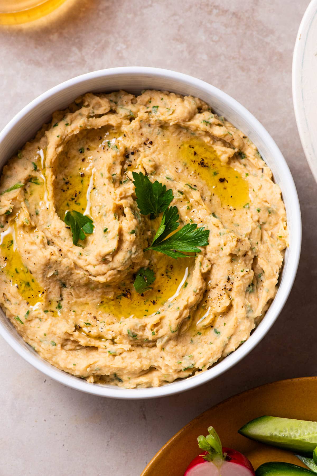 White bean dip garnished with olive oil and parsley.