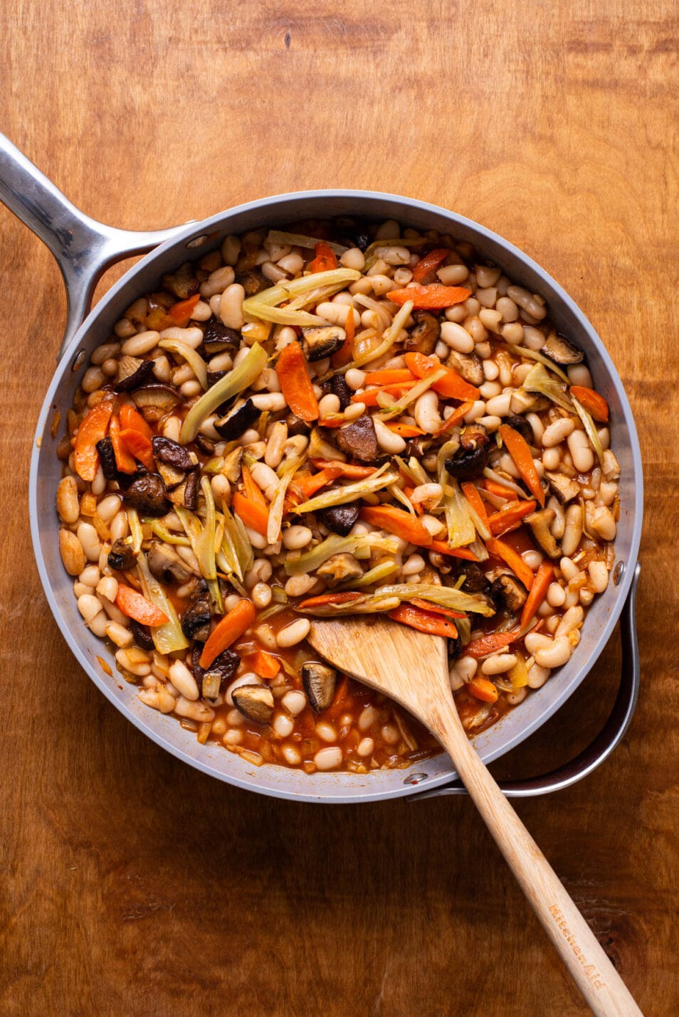White beans with roasted vegetables stirred together in a skillet.