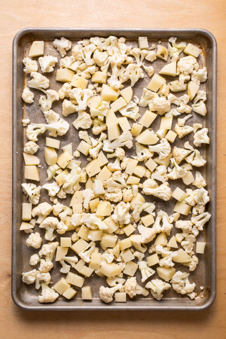 Chopped potatoes and cauliflower on a baking sheet.