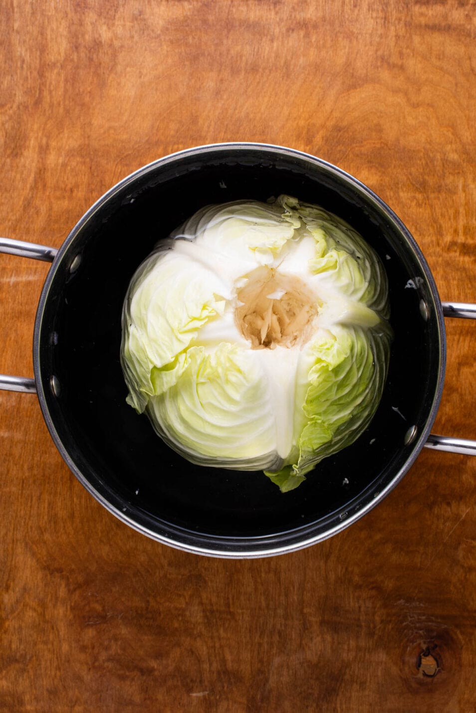 Cored green cabbage in a pot of water.