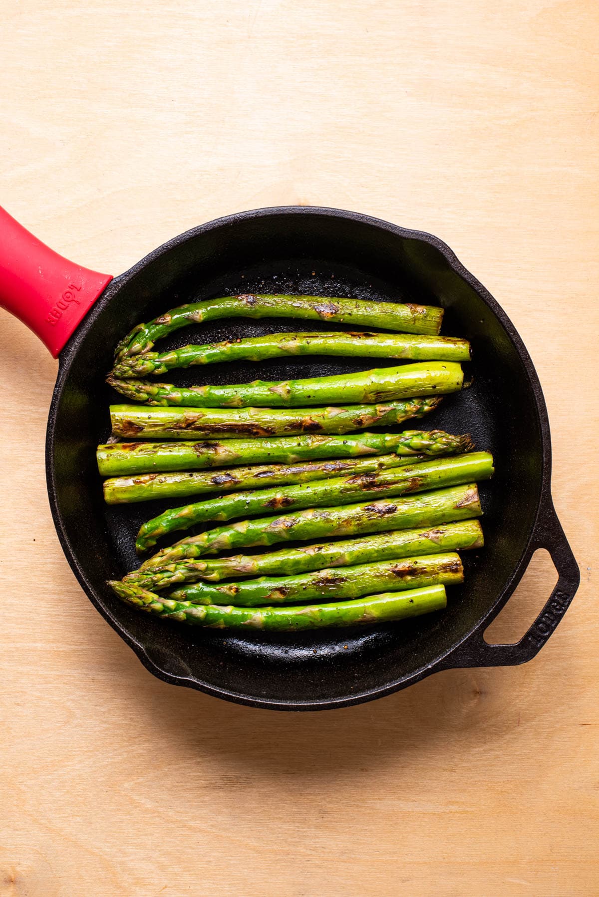 Seared asparagus in a cast iron skillet.
