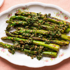Pan-fried asparagus spears with lemon-caper relish on an oval platter.