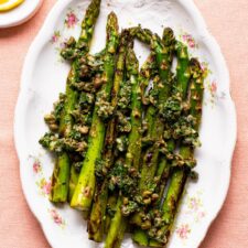 Pan-fried asparagus spears with lemon-caper relish on an oval platter.