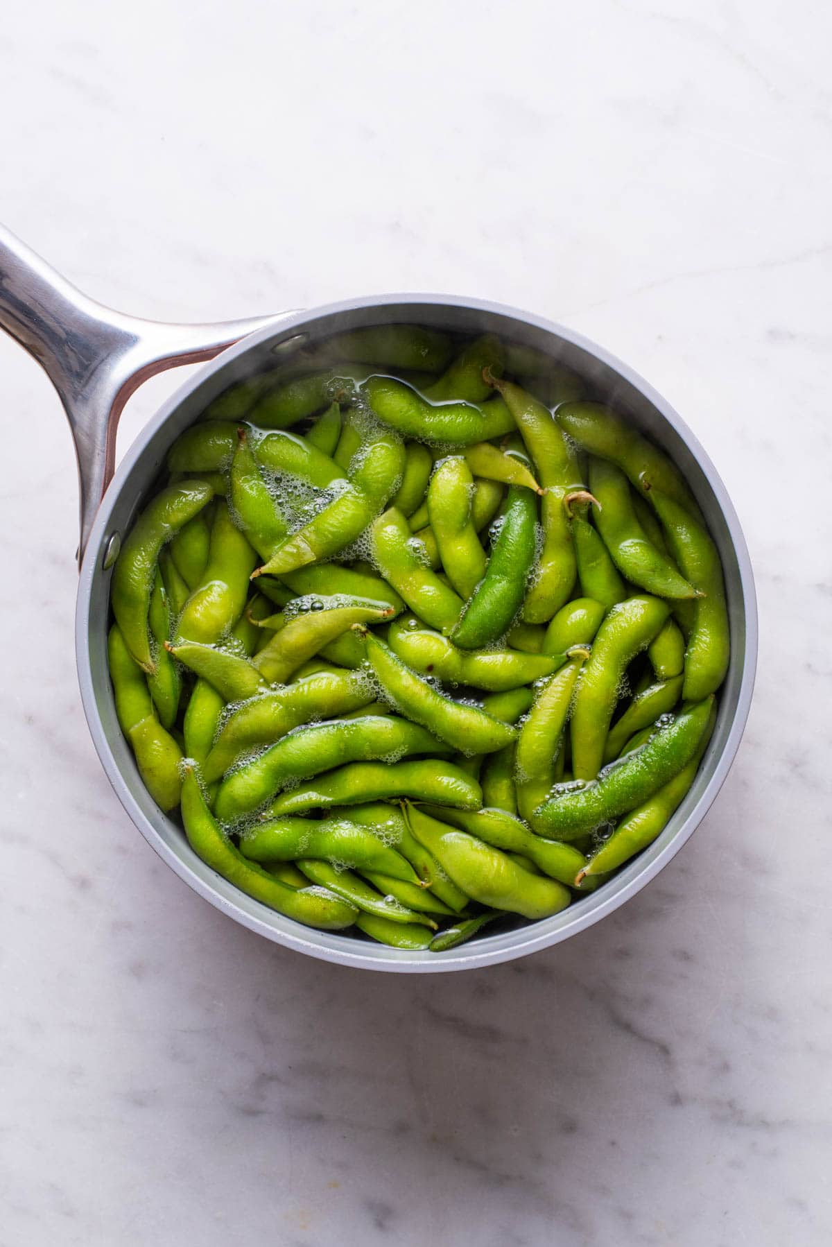 Boiling edamame pods in a pot of water.