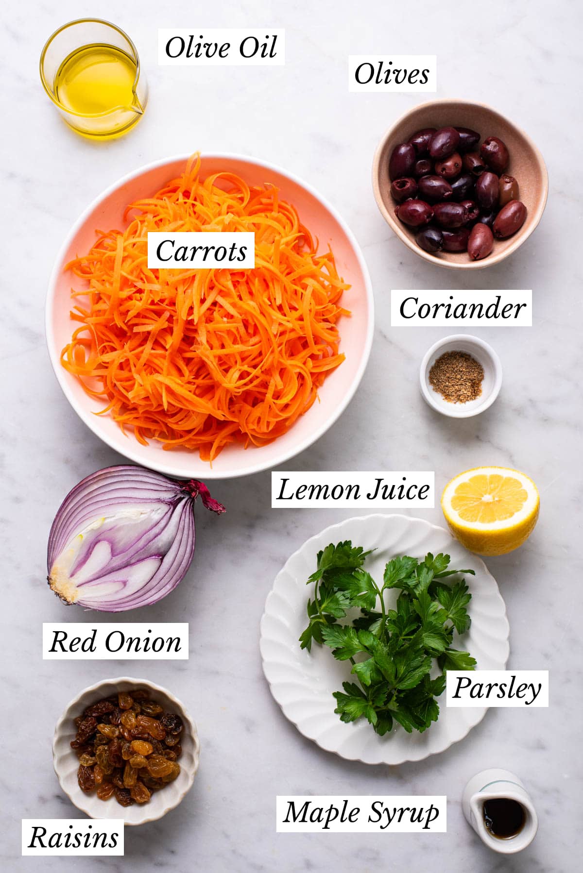 Ingredients gathered to make raw shredded carrot salad with raisins and olives.