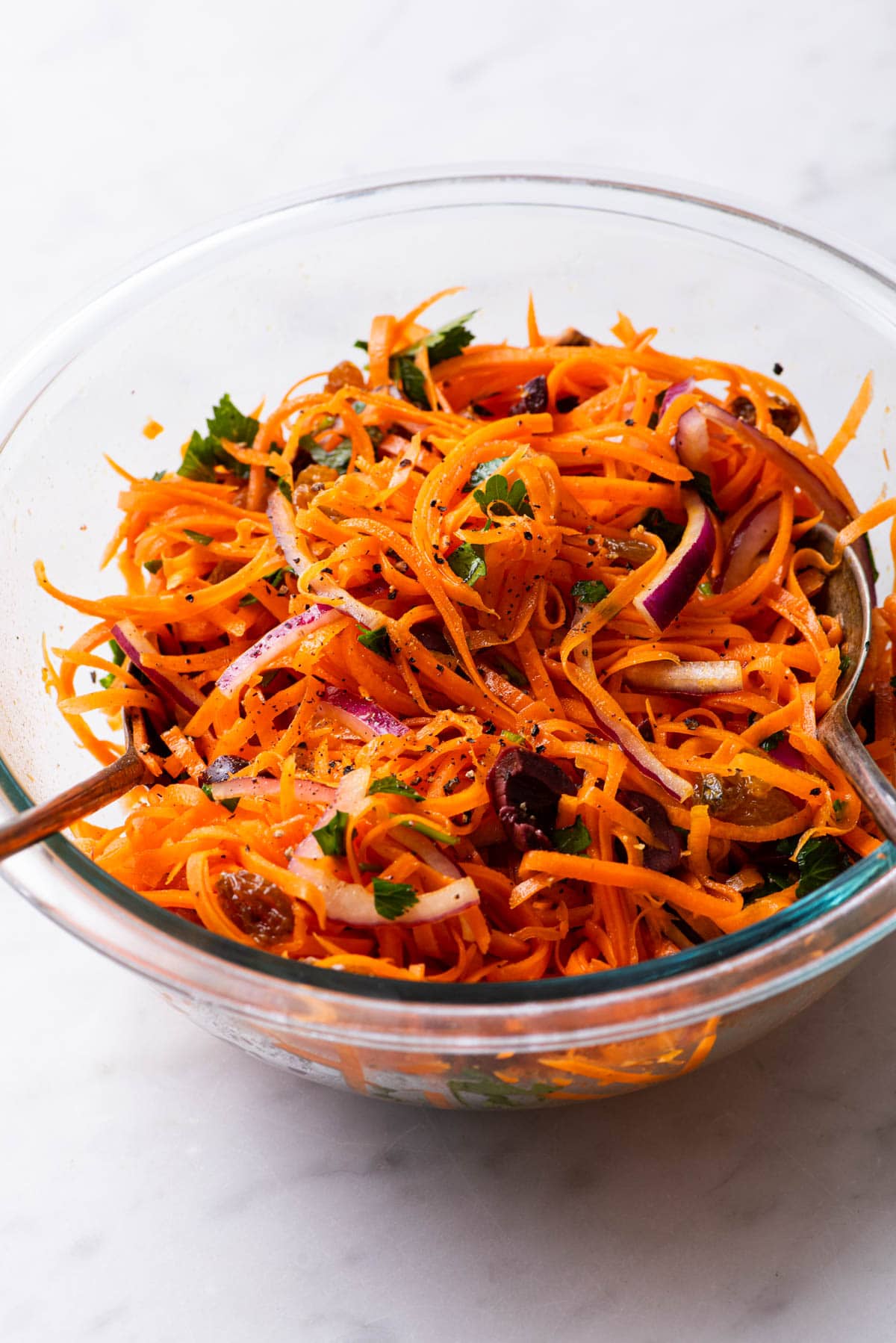 Shredded carrot slaw with raisins, parsley, olives, and red onion.