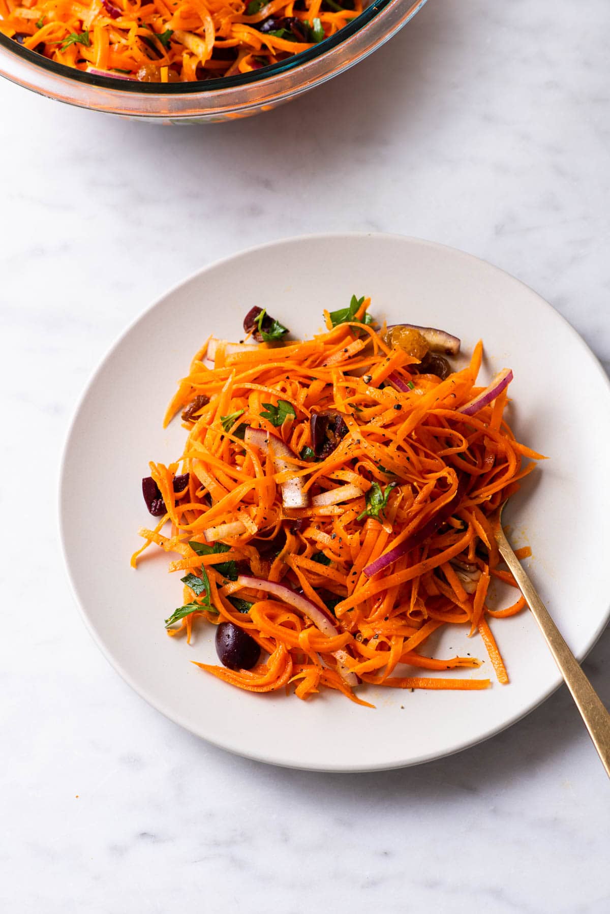 Moroccan shredded carrot salad with raisins on a white plate.