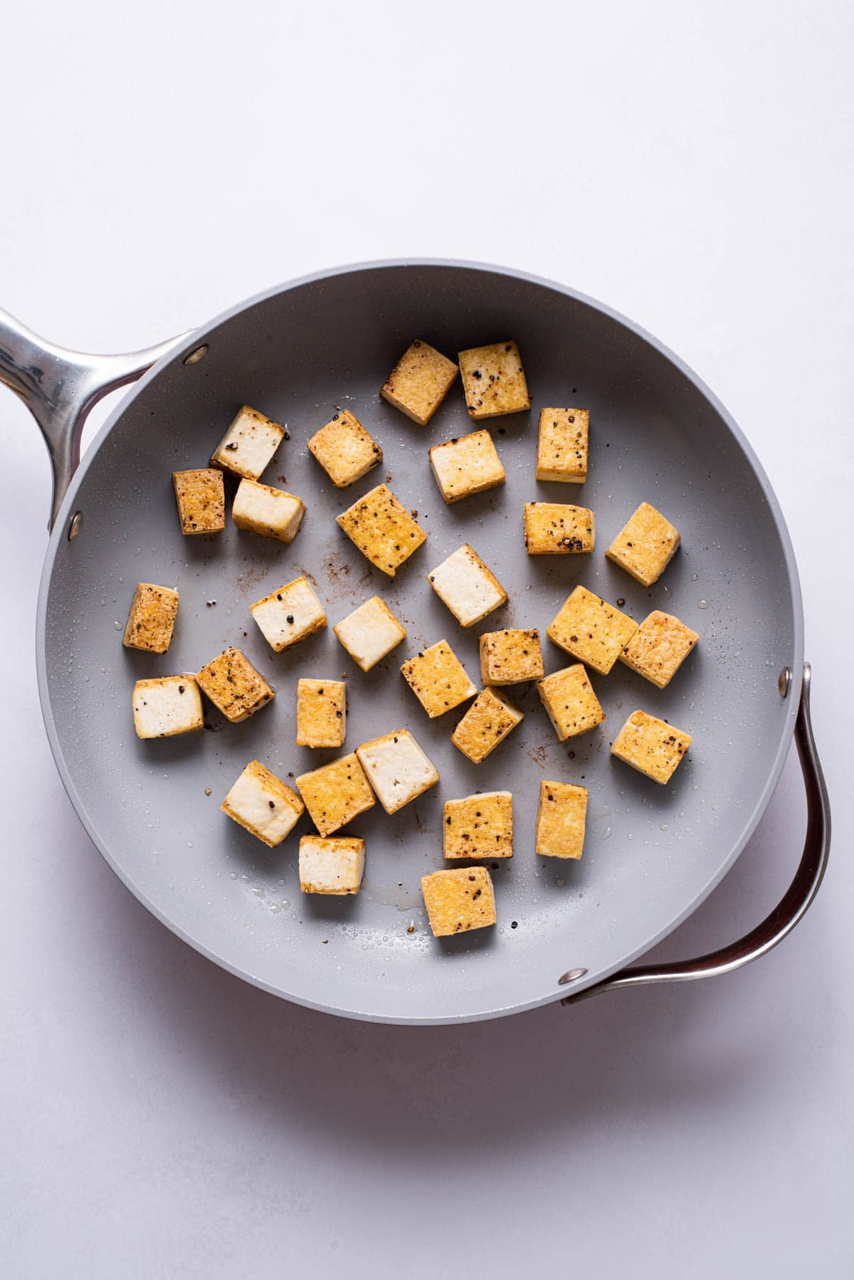 Crispy tofu cubes in a skillet.