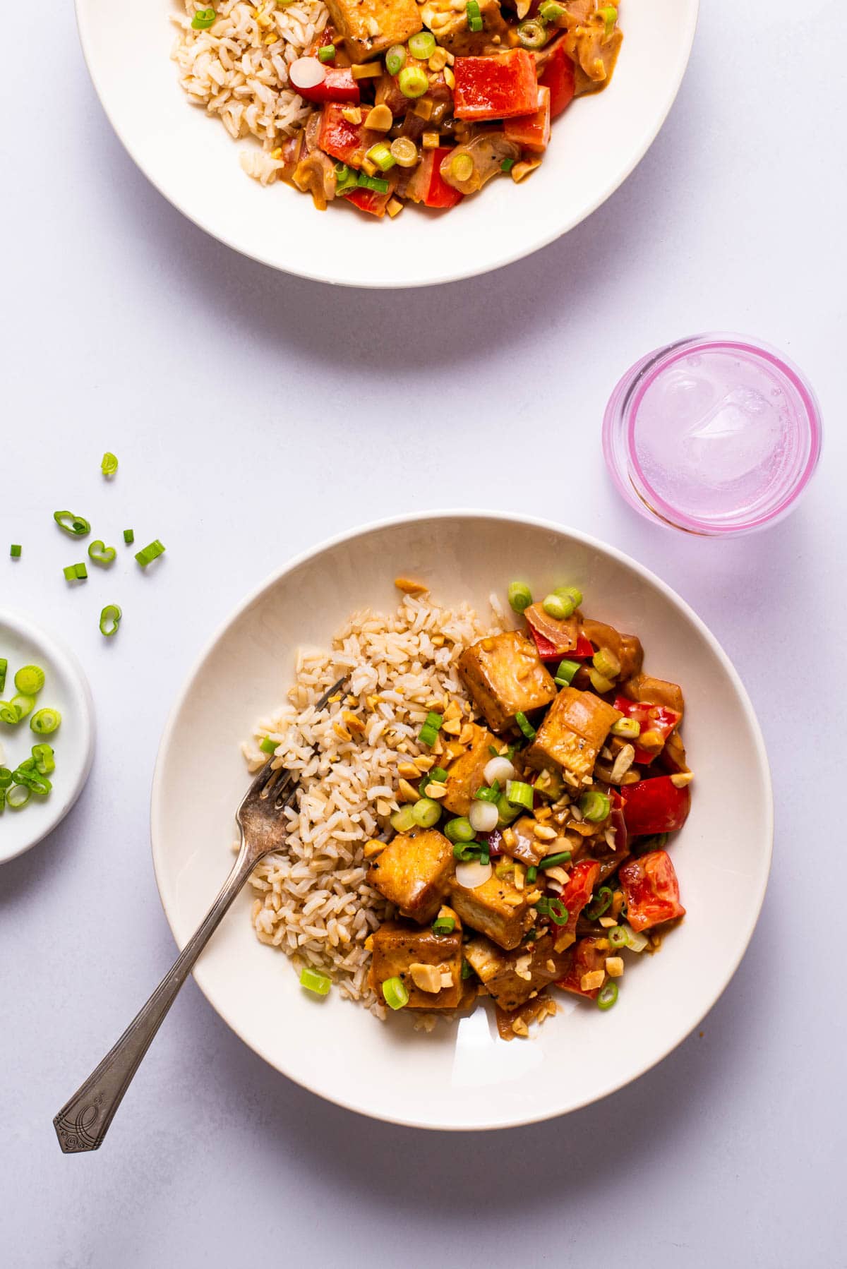 Peanut butter tofu stir-fry in white bowls with brown rice.