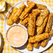 Air fryer zucchini fries next to spicy mayo on a white plate.