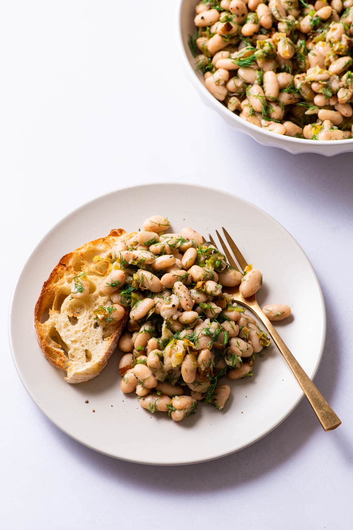 Herby white bean salad on a plate with toast.