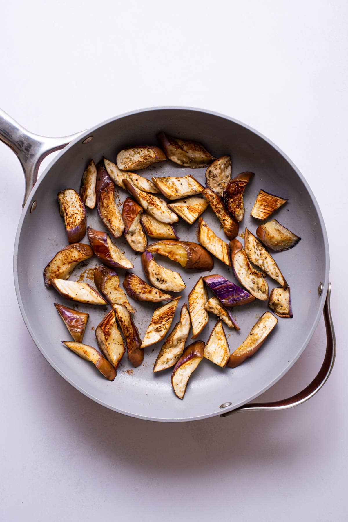 Browned Chinese eggplants in a skillet.