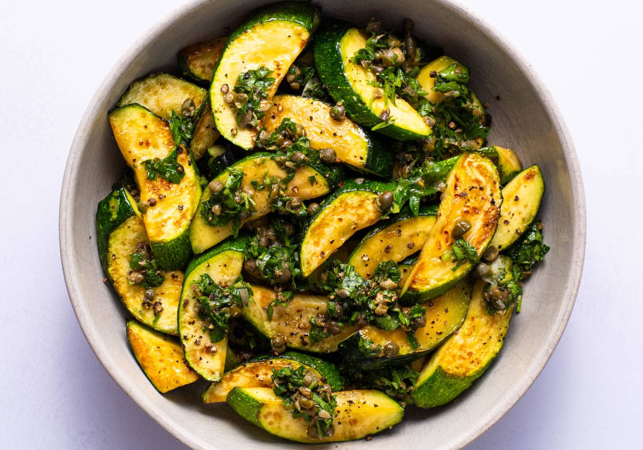 Pan-fried zucchini with caper relish in a bowl.