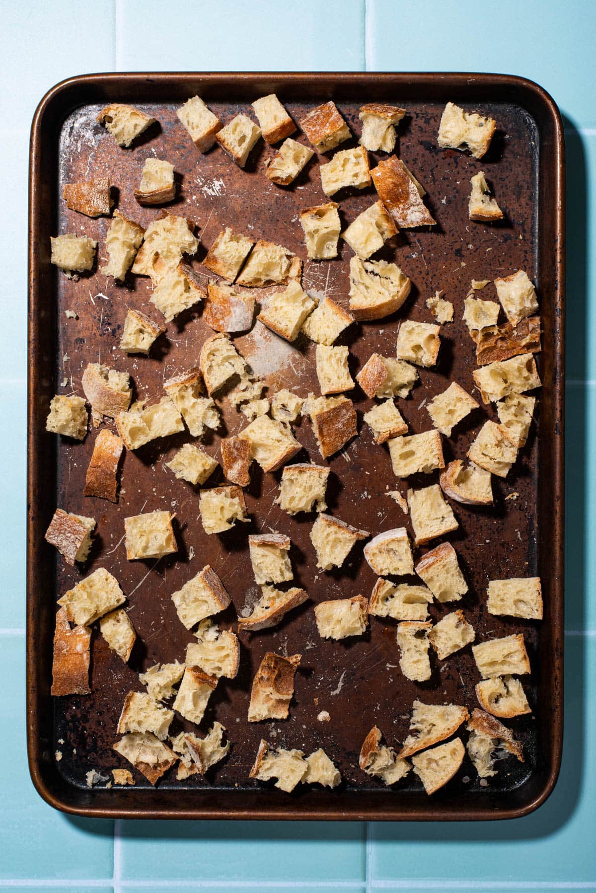 Toasted cubes of ciabatta on a baking sheet.
