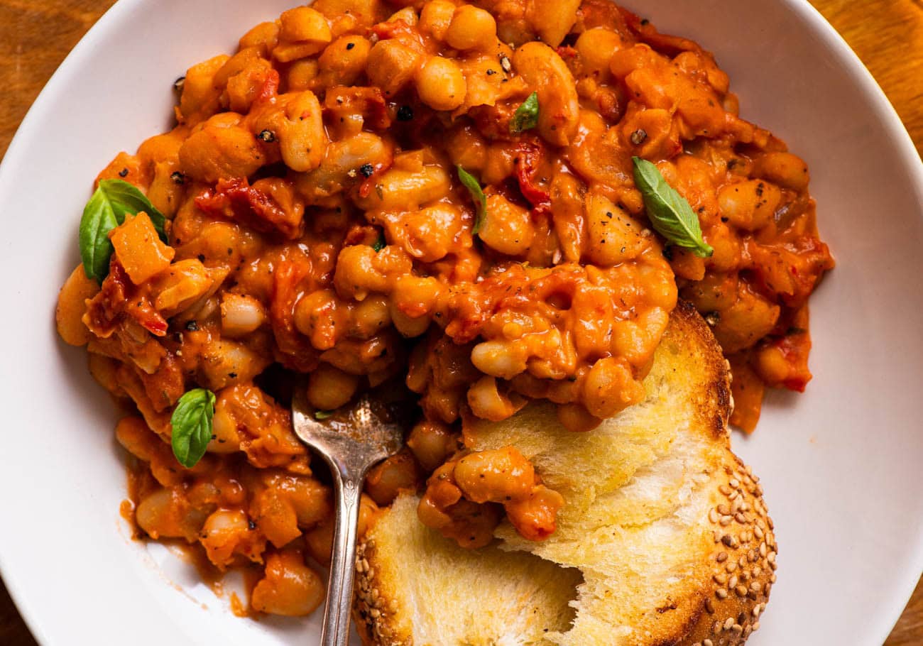 Tomato white beans with grilled bread, on a plate.